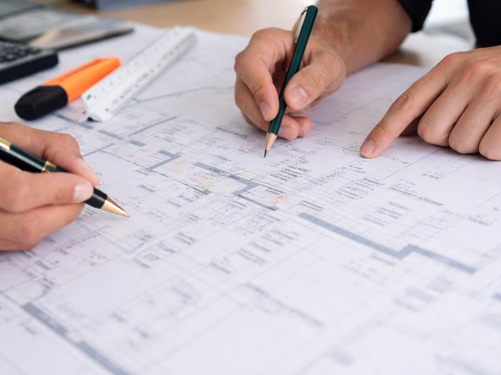 H&auml;nde bei einer Planbesprechung &uuml;ber Bauzeichnungen mit Stift und Lineal – technische Beratung und Projektplanung